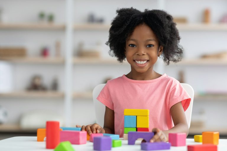 Portrait of cheerful adorable kid playing with wood blocks